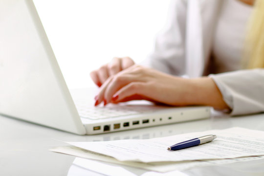 Close-up of businesswoman typing documents on keyboard of laptop