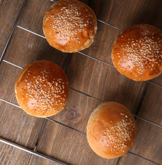 Tasty buns with sesame on oven-tray, on wooden background