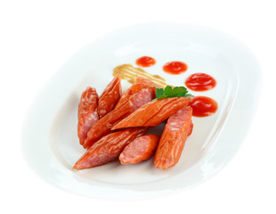 Smoked thin sausages and vegetables on plate, isolated on white