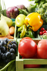 Fresh organic vegetables and fruits in wooden boxes, close up