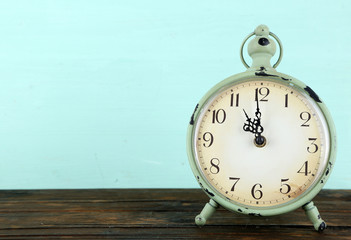 Old alarm clock on wooden table on blue background