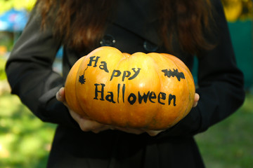 Young girl holding Halloween pumpkin, close-up, outdoors