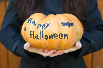 Young girl holding Halloween pumpkin, close-up, outdoors