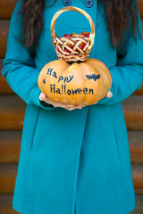 Young girl holding Halloween pumpkin and basket with candies,