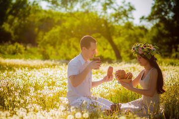 Young beautiful couple relaxing on the meadow with dandelions 
