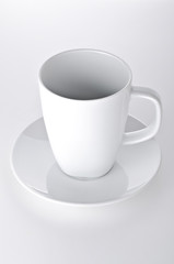 White cup with seucer isolated on gray background