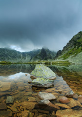 Mountain scenery with glacier lake, rocky peaks and stormy weather in summer, in the Alps