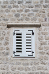 shuttered window in a stone wall of a house close-up