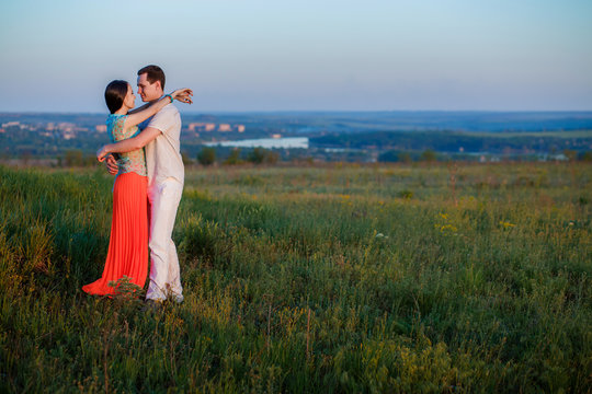 young beautiful couple on a cliff at sunset