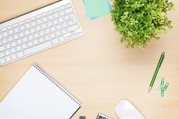 Office table with notepad, computer and flower