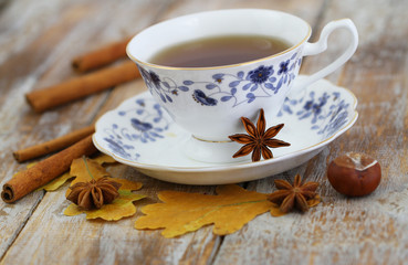 Fototapeta na wymiar Cup of tea, star anise, cinnamon, autumn leaves and chestnuts