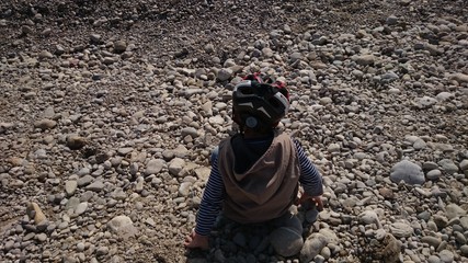 Kind sitzt auf steinen