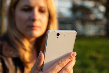 frau mit neutralem blick hält smartphone