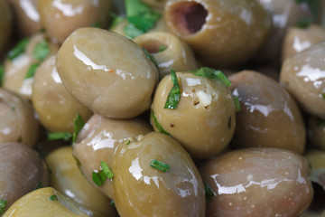 Green olives in oil with parsley close up. background