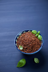 Ceramic pialat with raw red rice, dark blue wooden background