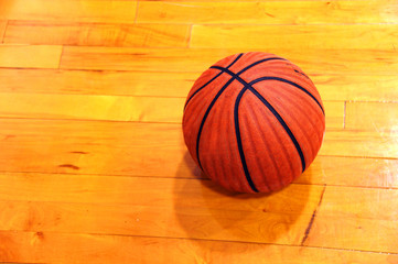 At basketball practice, a lone basketball sits on basketball court.