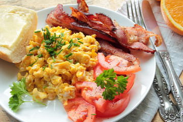 Breakfast with scrambled eggs with chive and bacon and tomatoes