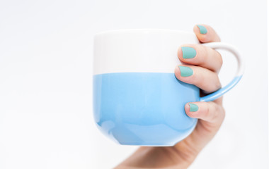 Hand with blue nails holding the blue mug