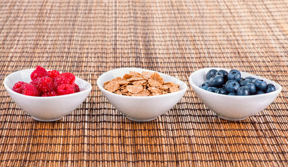 Bowls with blueberries, corn flakes and raspberries