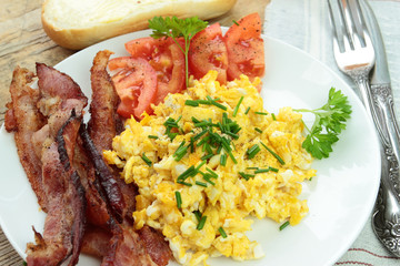 Tasty scrambled eggs with bacon and tomatoes