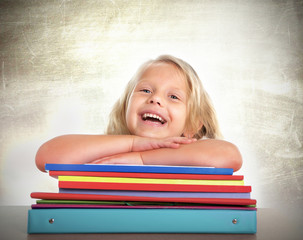 cute schoolgirl blonde hair happy on desk laughing and smiling
