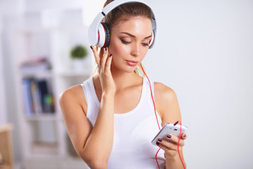 Naklejka premium Woman with headphone listening music standing at home