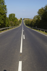 Obraz premium Gerade Straße in hügeliger Landschaft