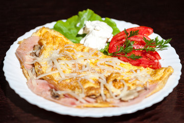 omelet with vegetables and tomatoes on wooden background