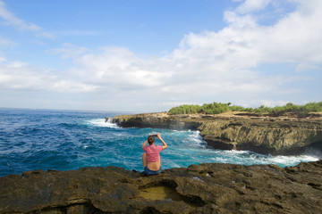 Girl taking photo with cellphone on the rock in Lembongan island