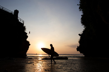 Surfer on the ocean beach near uluwatu spot at sunset on Bali is