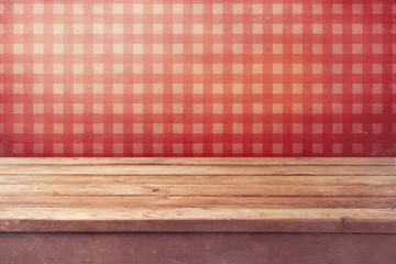 Empty wooden deck table over checked red wallpaper