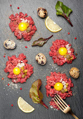 Beef tartare with egg, capers and onions on dark background