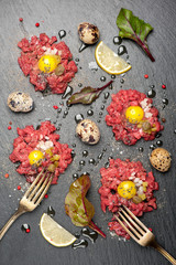 Beef tartare with egg, capers and onions on dark background