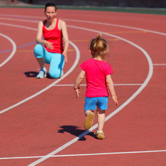 Obraz premium Mother and little daughter are running in the stadium.