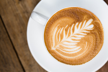 Cup of hot latte art coffee on wooden table