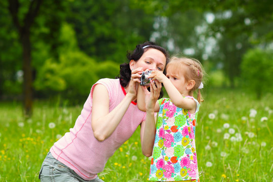 little girl child to learn to photograph with his mother
