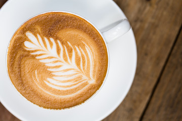 Cup of hot latte art coffee on wooden table