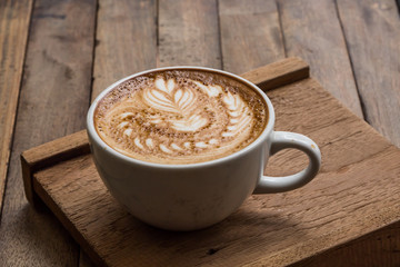 Cup of hot latte art coffee on wooden table