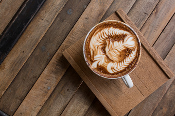Cup of hot latte art coffee on wooden table
