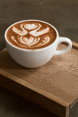 Cup of hot latte art coffee on wooden table