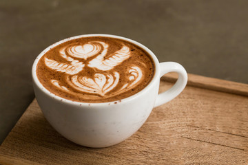 Cup of hot latte art coffee on wooden table