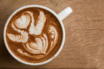 Cup of hot latte art coffee on wooden table