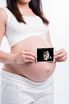 pregnant woman holding ultrasound scan on her tummy