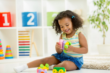 Kid girl playing toys at kindergarten room