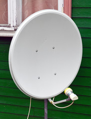 Satellite TV antenna on the wall of a wooden house
