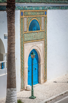 A blue door with black studs and stone ornament at doorway in Tu