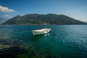 Fototapeta na wymiar Kotor bay with moored white wooden rowboat