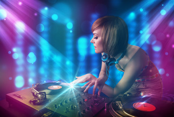 Obraz na płótnie Canvas Dj girl mixing music in a club with blue and purple lights