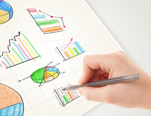 Business person drawing colorful graphs and icons on paper