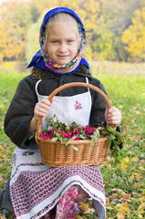 Маленькая девочка на осенней поляне, с корзиной рябины